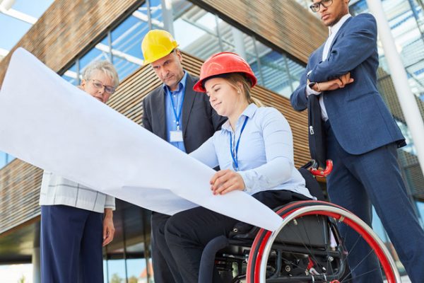 What to Understand About the Power of Inclusive Hiring Disabled woman as an architect in a wheelchair with blueprint together with engineers