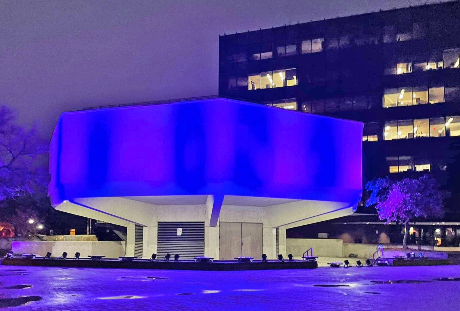 Octagonal North Bay City Hall building glowing with purple light.