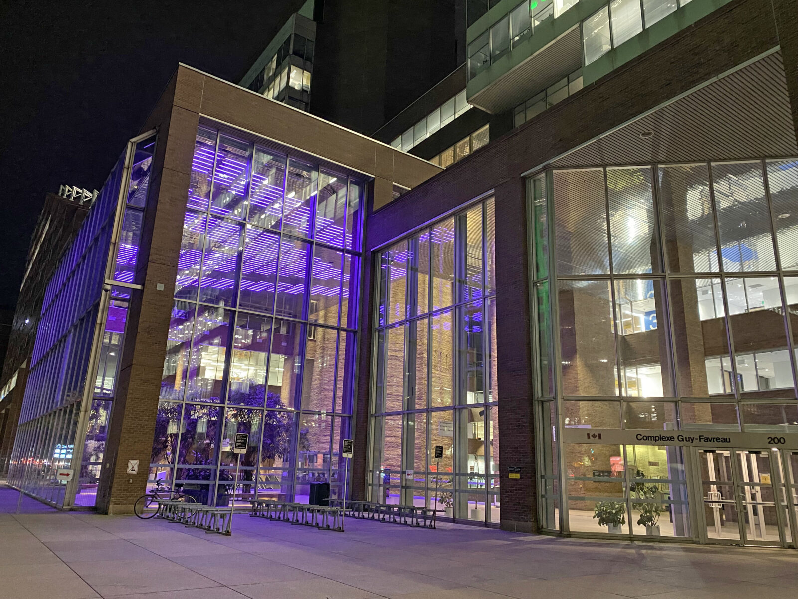 The interior lobby ceiling lights of the federal Complexe Guy-Favreau building in Montreal are illuminated purple.